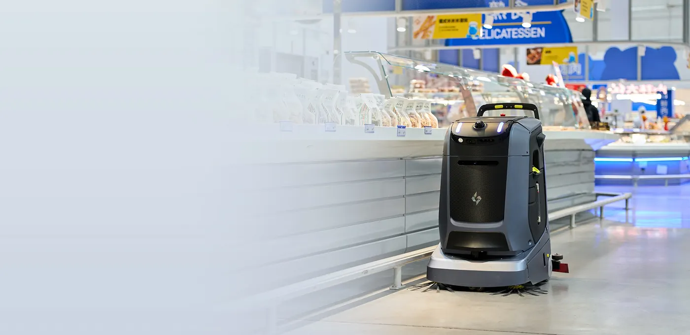 Gausium Mira : Bannière d'accueil : Mira devant un comptoir traiteur de supermarché, moitié gauche en dégradé clair pour le texte (2315×1125).