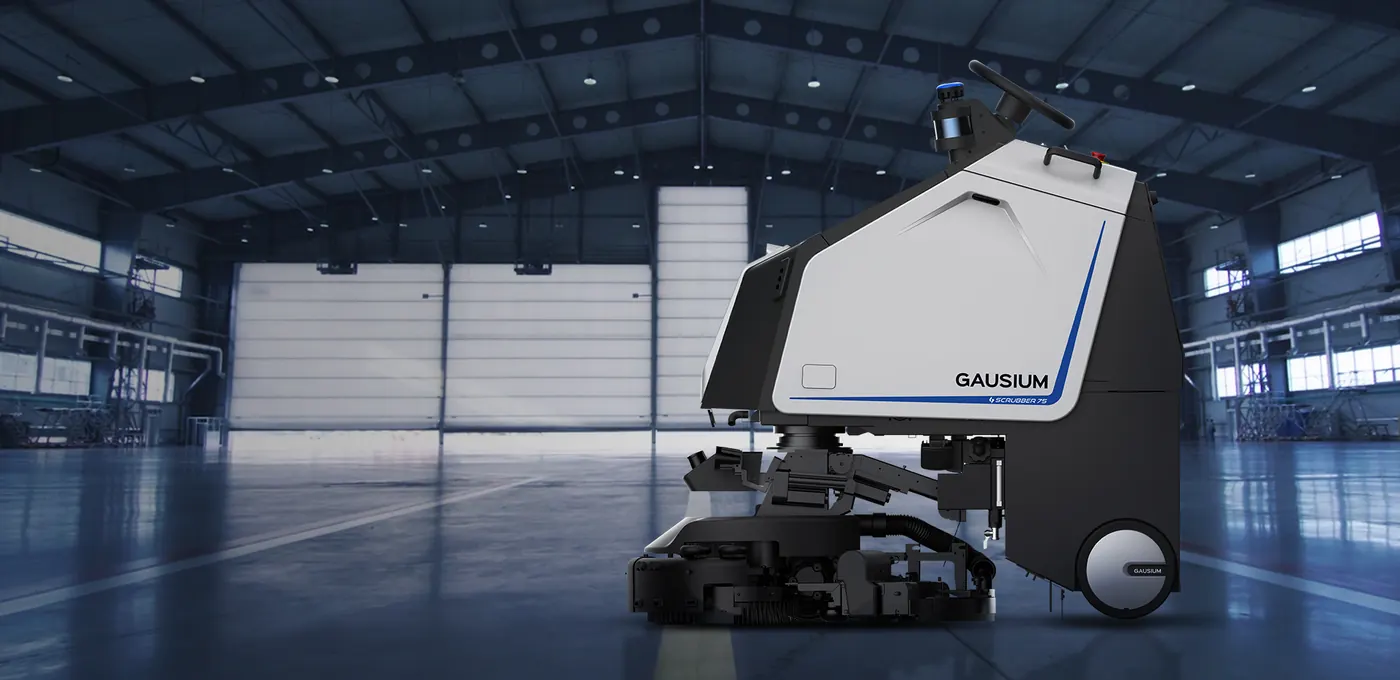 Gausium Scrubber 75 : Bannière : Scrubber 75 de profil dans un grand hangar industriel, espace libre à gauche (1920×933).