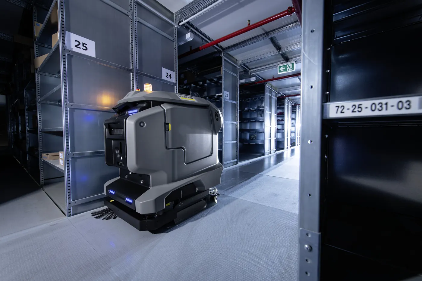 Robot Kärcher KIRA B 50 dans une allée d'entrepôt bordée de rayonnages métalliques